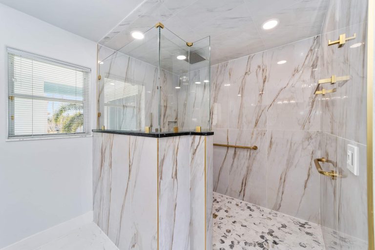Walk-in shower with marble tile and gold fixtures